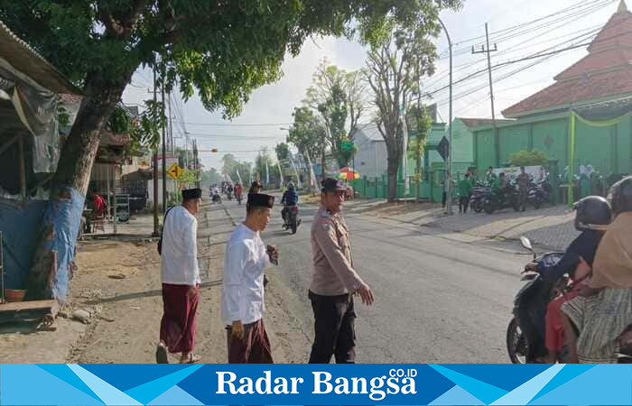 Petugas Polsek Tikung bersama warga mengatur arus lalu lintas di depan Kantor MWC NU Tikung, Lamongan, saat pelaksanaan Apel Hari Santri Nasional 2025, Rabu (22/10/2025) pagi. (Foto Dok Ho/RadarBangsa.co.id)