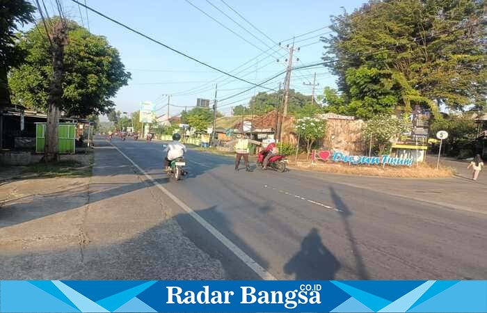 Anggota Polsek Tikung mengatur arus lalu lintas dan membantu warga menyeberang saat pelaksanaan Commander Wish di Simpang Tiga Tikung, Lamongan, Rabu (15/10/2025) pagi. (Foto Dok Ho/RadarBangsa.co.id)