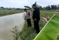 Anggota Polsek Tikung meninjau kondisi saluran irigasi di wilayah rawan banjir Kecamatan Tikung, Lamongan, saat pelaksanaan Patroli Kota Presisi, Minggu (5/10) (Foto Dok Ho/RadarBangsa.co.id)