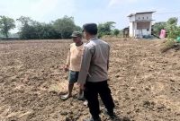 Anggota Polsek Tikung berbincang dengan warga saat patroli di area program Pekarangan Pangan Bergizi (P2B) di Desa Botoputih, Kecamatan Tikung, Kabupaten Lamongan, Minggu (5/10/2025).