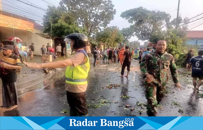 Personel Polsek Tikung bersama anggota TNI dan warga bergotong royong membersihkan pohon tumbang pasca angin kencang melanda Kecamatan Tikung, Lamongan, Rabu (8/10/2025). (Foto Dok Ho/RadarBangsa.co.id)