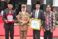 Asisten Pemerintahan dan Kesra Bangkalan Moawi Arifin bersama Kepala Bakesbangpol Moch. Musleh menerima trofi peringkat 1 penanganan konflik sosial se-Jawa Timur 2024. Foto Dok Ho/RadarBangsa.co.id