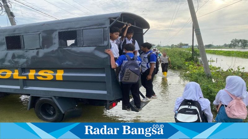 Petugas Satsamapta Polres Lamongan mengantar pelajar di wilayah banjir Kalitengah, Lamongan, Kamis (30/1/2026). (Foto Dok Ho/Nul-RadarBangsa.co.id)
