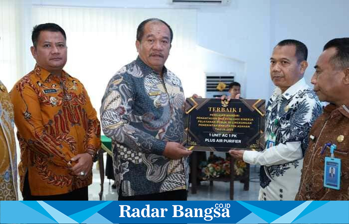 Bupati Asahan Taufik Zainal Abidin Siregar menyerahkan piagam penghargaan kepada Kepala Dinas Kependudukan dan Pencatatan Sipil Kabupaten Asahan Rahmanto, Jumat (23/1/2026). (Foto Dok Ho/Dicky-RadarBangsa.co.id)
