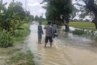 Anggota Polsek Tikung melakukan monitoring genangan air di Jalan Raya Sarirejo–Bakalanpule, Kecamatan Tikung, Lamongan, Kamis (5/2/2026). (Foto Dok Ho/RadarBangsa.co.id)