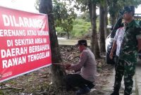 Petugas Polsek Tikung bersama Babinsa memasang banner larangan berenang di waduk depan SDN Gumingrejo, Rabu (18/2/2026). (Foto Dok Ho/RadarBangsa.co.id)