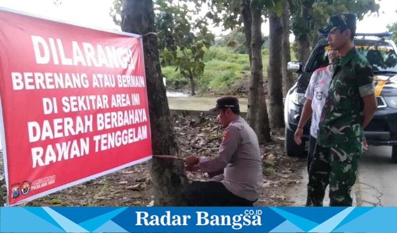 Petugas Polsek Tikung bersama Babinsa memasang banner larangan berenang di waduk depan SDN Gumingrejo, Rabu (18/2/2026). (Foto Dok Ho/RadarBangsa.co.id)