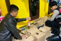 Petugas Sat Samapta Polres Lamongan menunjukkan ratusan botol miras hasil operasi di Brondong, Selasa (10/2). (Foto Dok Ho/RadarBangsa.co.id)