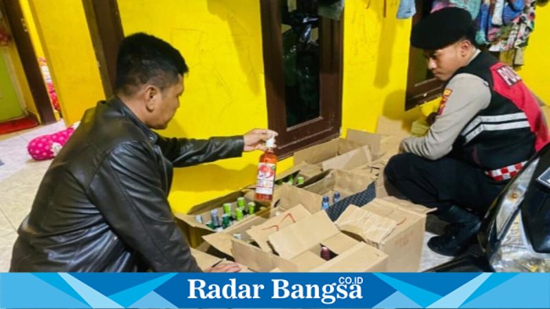 Petugas Sat Samapta Polres Lamongan menunjukkan ratusan botol miras hasil operasi di Brondong, Selasa (10/2). (Foto Dok Ho/RadarBangsa.co.id)