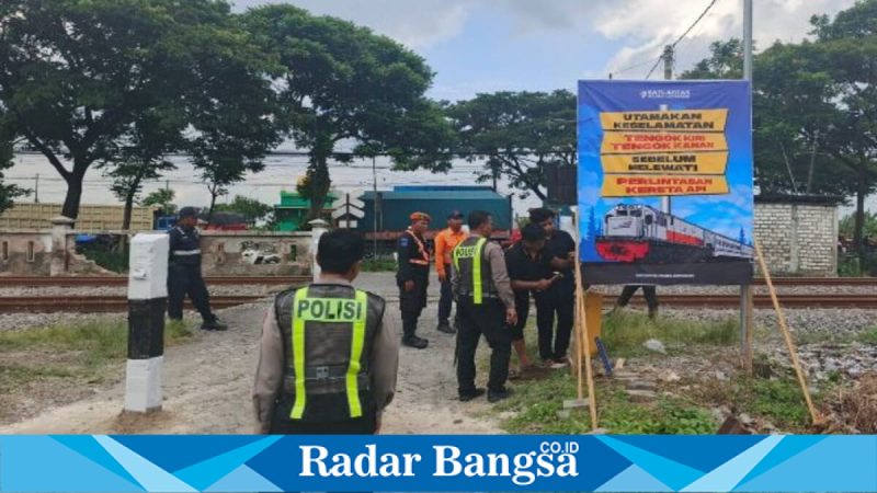 Petugas Satlantas Polres Lamongan memasang banner imbauan keselamatan di Perlintasan Sebidang JPL 266 Babat, Jumat (6/2/2026). (Foto Dok Ho/RadarBangsa.co.id)