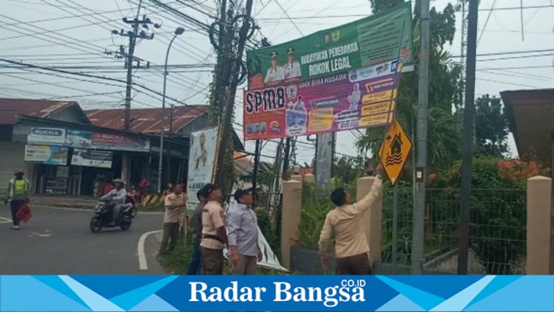 Petugas Satpol PP Pamekasan menurunkan reklame melanggar Perbup Nomor 33 Tahun 2025, Jumat (6/2/2026). (Foto Dok Ho/Deb-RadarBangsa.co.id)