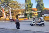 Petugas Jaga Polsek Laren, Aipda Andre, mengatur arus lalu lintas saat kedatangan siswa di SMPN 1 Brondong, Jumat (24/7/2026). (Foto Dok Ho/RadarBangsa.co.id)