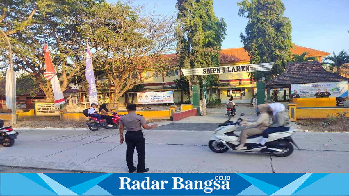 Petugas Jaga Polsek Laren, Aipda Andre, mengatur arus lalu lintas saat kedatangan siswa di SMPN 1 Brondong, Jumat (24/7/2026). (Foto Dok Ho/RadarBangsa.co.id)