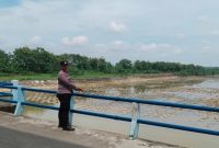 Petugas jaga Polsek Laren melakukan pemantauan debit air di Floodway Pelangwot atau Sudetan Bengawan Solo, Lamongan, Jumat (10/7/2026), sebagai langkah antisipasi banjir. (Foto Dok Ho/RadarBangsa.co.id)