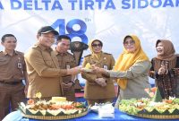 Bupati Sidoarjo Subandi memotong tumpeng sebagai simbol peringatan HUT ke-48 Perumda Delta Tirta di halaman kantor Perumda Delta Tirta, Sidoarjo, Senin (6/7/2026). (Foto Dok Ho/RadarBangsa.co.id)