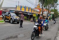 Petugas Polsek Laren melakukan pengaturan lalu lintas dan membantu penyeberangan warga di Perempatan Pasar Gobeh, Senin (20/7/2026). (Foto Dok Ho/RadarBangsa.co.id)