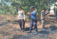 Petugas Polsek Kedungpring bersama Unit Damkar Ngimbang memadamkan kebakaran lahan di Desa Dradahblumbang, Lamongan, Selasa (14/7/2026). (Foto Dok Ho/RadarBangsa.co.id)