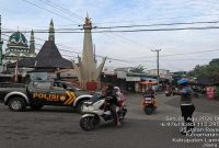 Personel Polsek Laren melaksanakan pengaturan arus lalu lintas dan membantu penyeberangan warga di Simpang Tiga Pasar Gobeh, Kecamatan Laren, Sabtu (1/8/2026). Foto Dok Ho/RadarBangsa.co.id.