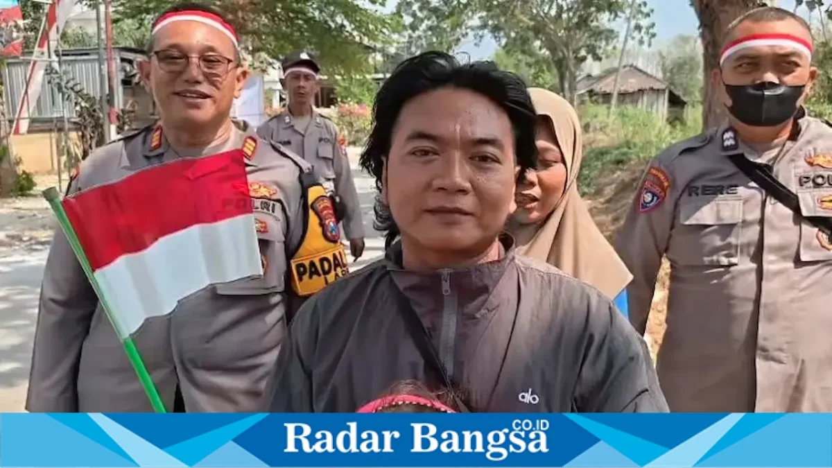 Personel Polres Lamongan membagikan dan memasang Bendera Merah Putih kepada masyarakat di sejumlah wilayah Kabupaten Lamongan, Minggu (16/8/2026). (Foto Dok Ho/RadarBangsa.co.id)