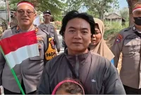 Personel Polres Lamongan membagikan dan memasang Bendera Merah Putih kepada masyarakat di sejumlah wilayah Kabupaten Lamongan, Minggu (16/8/2026). (Foto Dok Ho/RadarBangsa.co.id)
