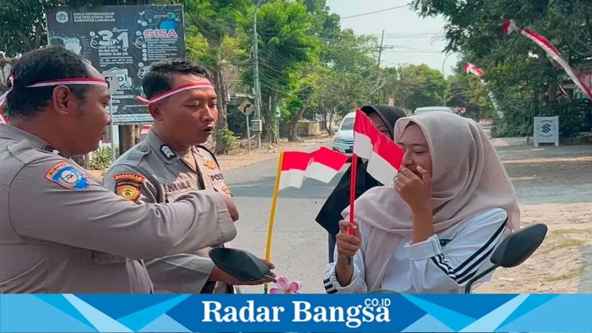 Personel Polsek Tikung membagikan Bendera Merah Putih kepada masyarakat dan pengguna jalan di depan Mako Polsek Tikung, Minggu (16/8/2026). (Foto Dok Ho/RadarBangsa.co.id)