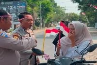 Personel Polsek Tikung membagikan Bendera Merah Putih kepada masyarakat dan pengguna jalan di depan Mako Polsek Tikung, Minggu (16/8/2026). (Foto Dok Ho/RadarBangsa.co.id)