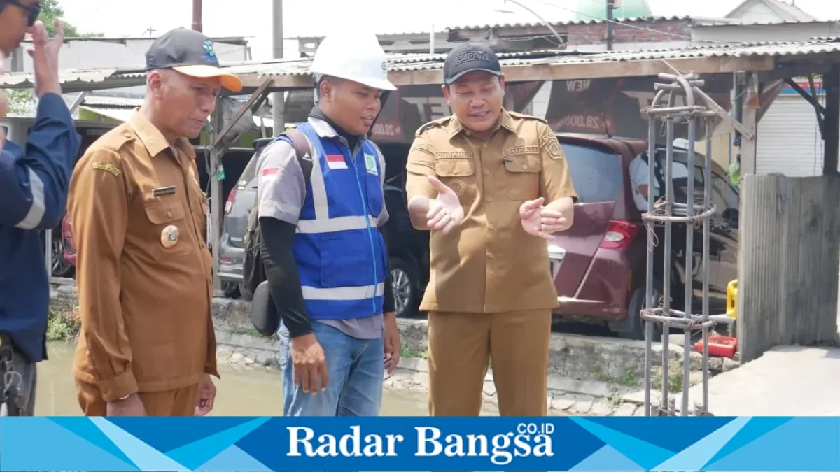 Bupati Sidoarjo Subandi meninjau kondisi sungai di sekitar proyek betonisasi Jalan Gedangan–Betro dan menjelaskan kendala penataan sungai kepada petugas di lokasi, Senin (12/10/2026). (Dok. RadarBangsa.co.id)