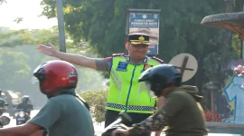 Kapolres Lamongan AKBP Adhytiawarman Gautama Putra saat mengatur lalu lintas dan membantu penyeberangan anak sekolah di Lamongan, Senin (19/10/2026). (Dok. Ho/Polres Lamongan)