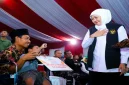 Gubernur Jawa Timur Khofifah Indar Parawansa menyerahkan bantuan dalam kegiatan Sapa Bansos dan Bakti Sosial di Pantai Slopeng, Sumenep, Rabu (14/10/2026). (Dok. Ho/RadarBangsa.co.id)